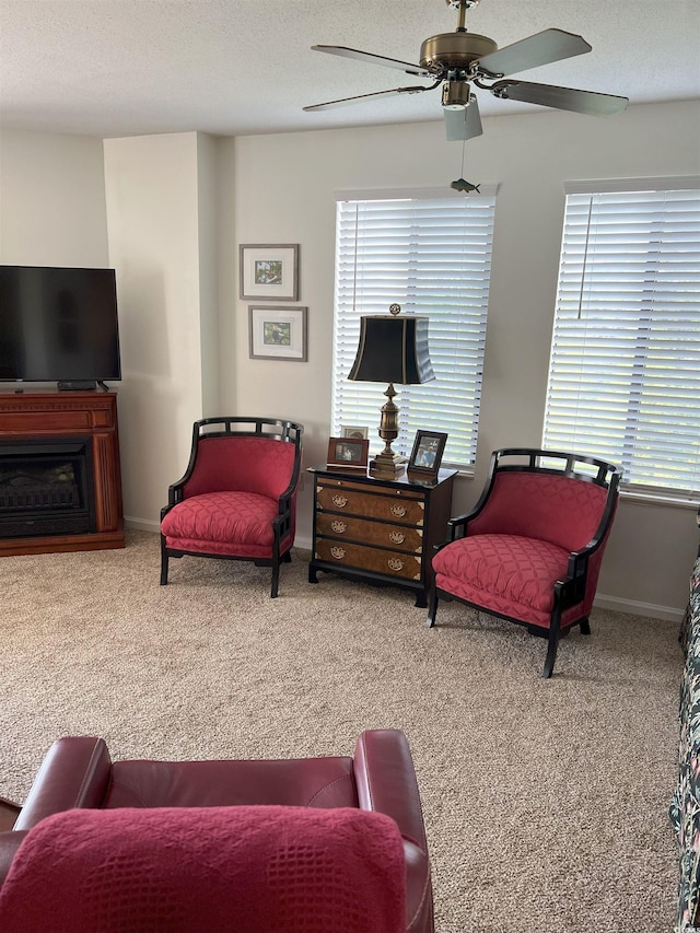 carpeted living area featuring ceiling fan, baseboards, and a textured ceiling