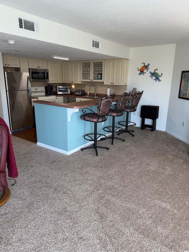 310 N 73rd Ave N Unit 5D, Myrtle Beach, SC 29572 - kitchen featuring stainless steel appliances, cream cabinetry, a kitchen bar, a sink, and a textured ceiling