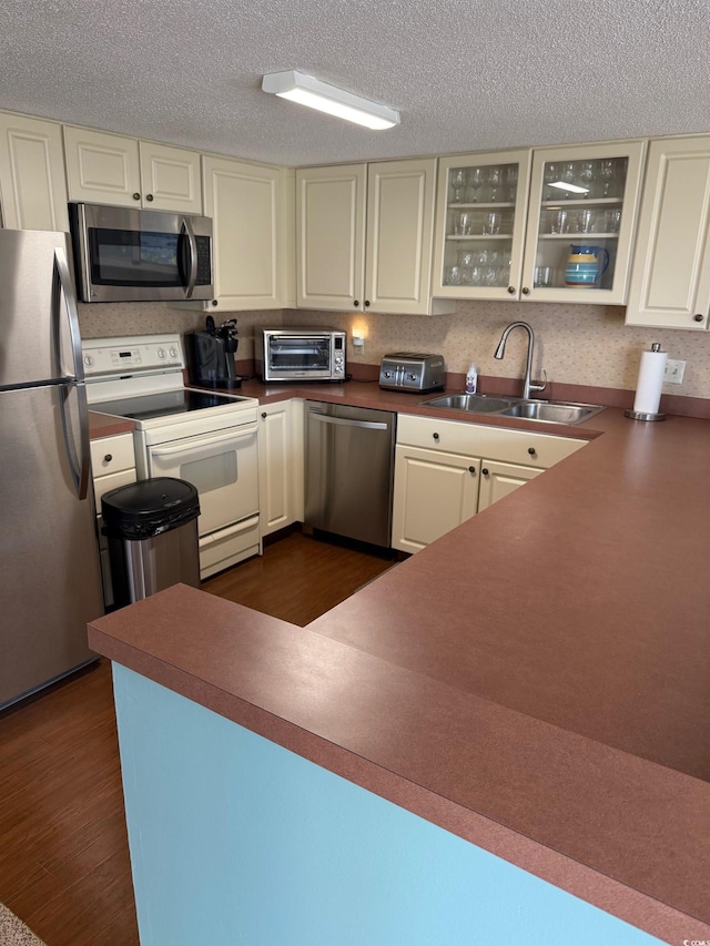 310 N 73rd Ave N Unit 5D, Myrtle Beach, SC 29572 - kitchen featuring appliances with stainless steel finishes, a sink, dark wood-style flooring, glass insert cabinets, and a textured ceiling