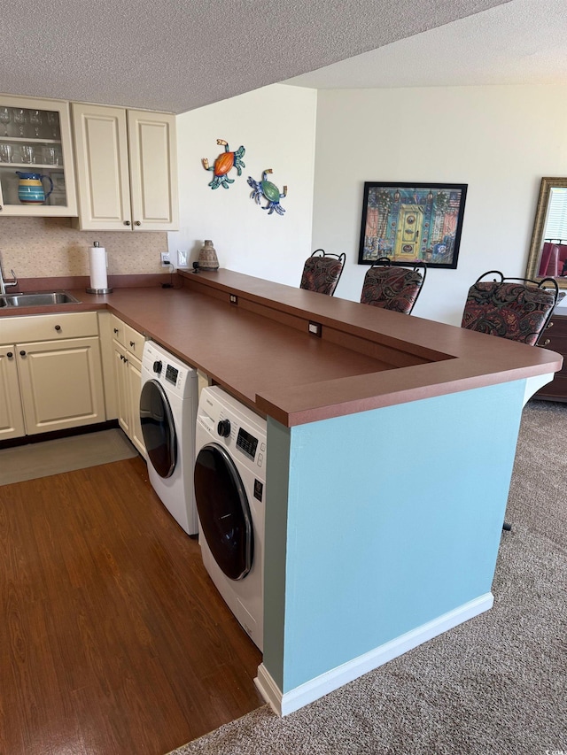 laundry area with independent washer and dryer, cabinet space, a textured ceiling, and dark wood finished floors