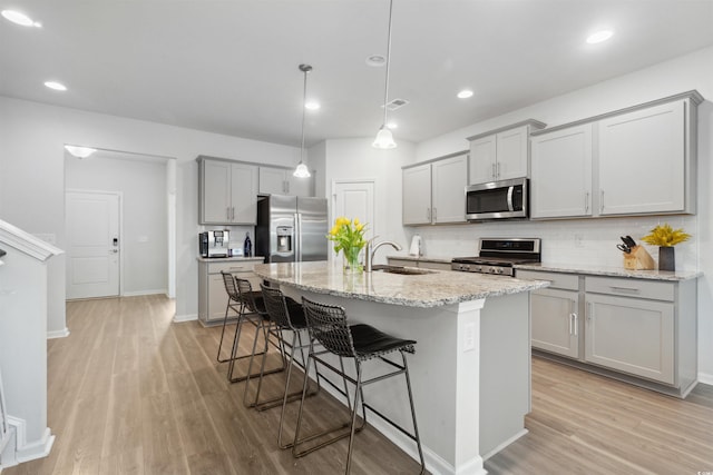 kitchen featuring gray cabinetry, backsplash, stainless steel appliances, and a sink