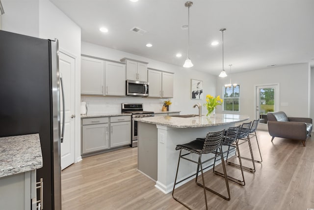 kitchen with visible vents, a breakfast bar, light wood-type flooring, tasteful backsplash, and stainless steel appliances