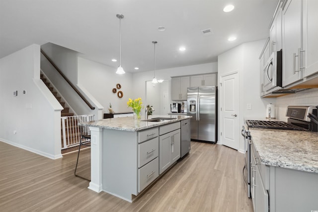 kitchen featuring a sink, gray cabinets, light wood-style flooring, and stainless steel appliances