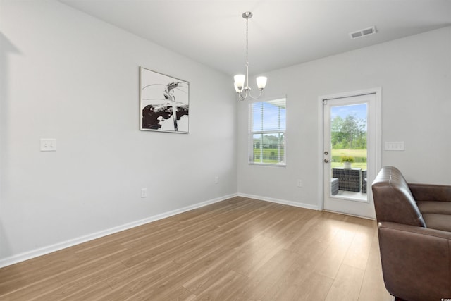 interior space with baseboards, a notable chandelier, light wood-style flooring, and visible vents