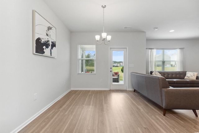 living area featuring light wood-style floors, a healthy amount of sunlight, visible vents, and a chandelier