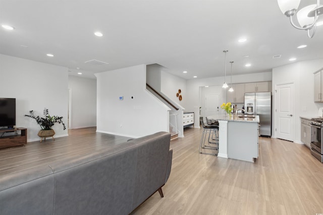 living area with recessed lighting, light wood-style flooring, and stairway