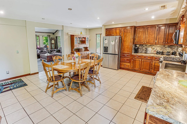 kitchen with tasteful backsplash, light tile patterned floors, appliances with stainless steel finishes, and brown cabinetry