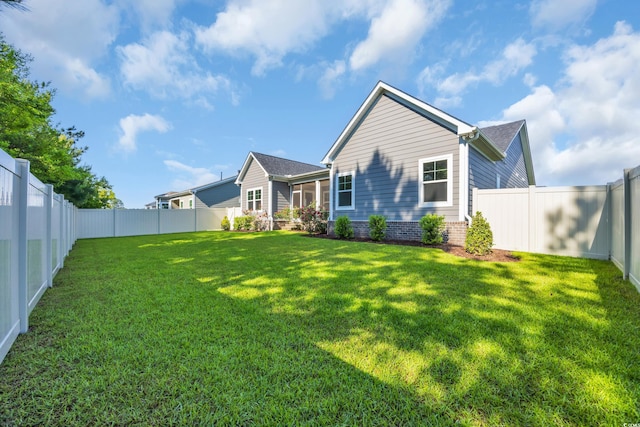 back of house with a lawn and a fenced backyard