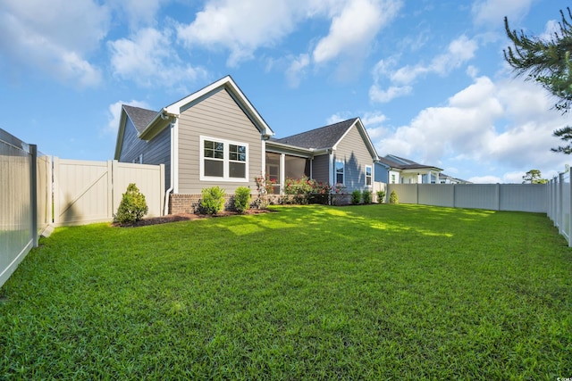 rear view of house featuring a yard, a gate, and a fenced backyard