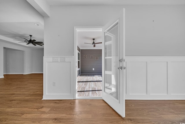 entrance foyer featuring ceiling fan, wood finished floors, a decorative wall, and a wainscoted wall