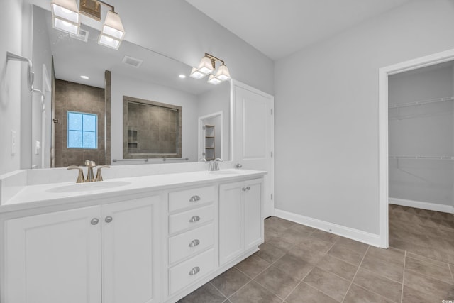 full bath with double vanity, a sink, a walk in shower, and baseboards