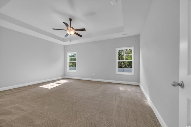carpeted empty room featuring baseboards, ceiling fan, and a tray ceiling