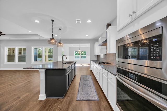 kitchen featuring visible vents, dark wood-style floors, white cabinets, a sink, and appliances with stainless steel finishes