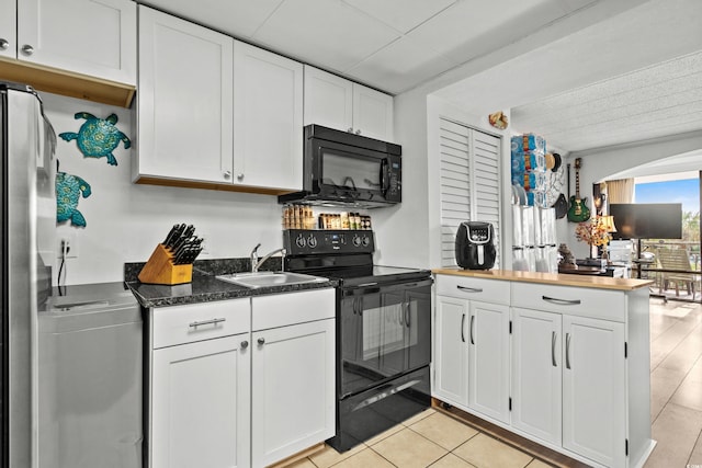 kitchen with washer / dryer, a peninsula, white cabinets, a sink, and black appliances