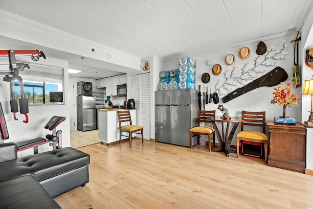 living area with ornamental molding and light wood-style flooring