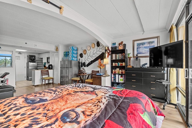 bedroom with ornamental molding, freestanding refrigerator, and light wood-style flooring