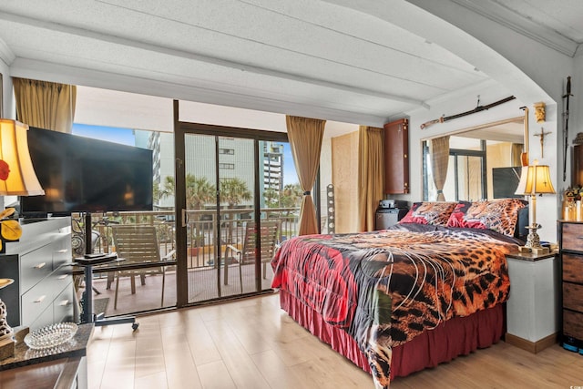 bedroom with crown molding, multiple windows, wood finished floors, and access to exterior