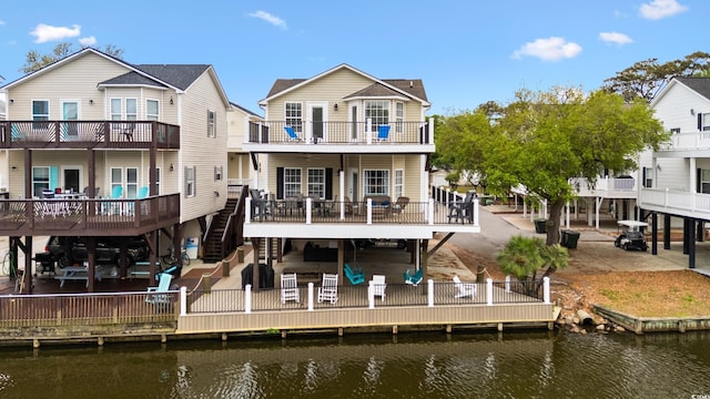 rear view of house featuring a patio area, stairs, a balcony, and a deck with water view