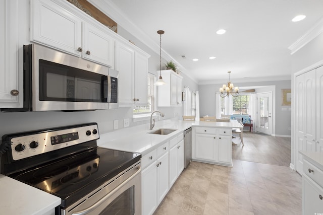 kitchen featuring stainless steel appliances, a sink, ornamental molding, a chandelier, and a peninsula