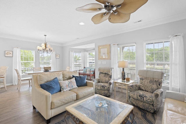 living area with plenty of natural light, ornamental molding, wood finished floors, a chandelier, and a ceiling fan