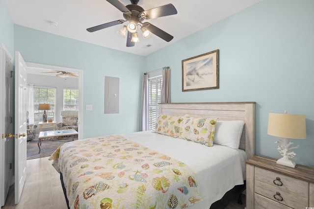 bedroom with wood finished floors, electric panel, and ceiling fan
