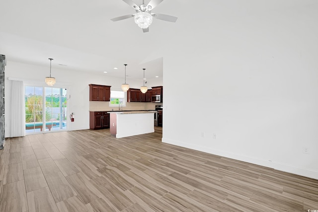 unfurnished living room with recessed lighting, ceiling fan, a sink, baseboards, and light wood-type flooring