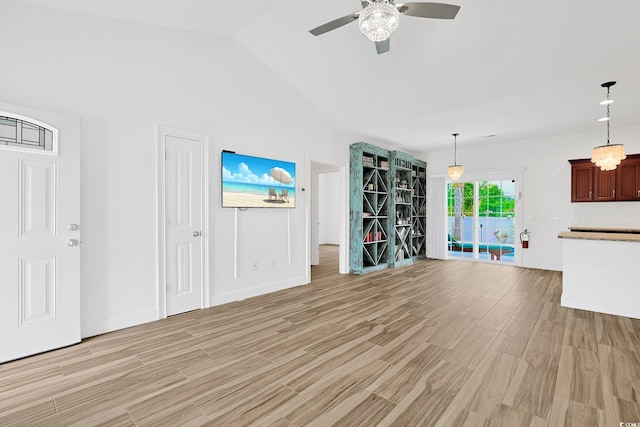 unfurnished living room with a ceiling fan, baseboards, lofted ceiling, and light wood-type flooring
