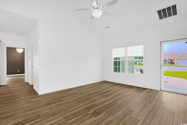 spare room featuring visible vents, wood finished floors, ceiling fan with notable chandelier, and plenty of natural light