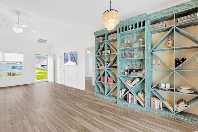 wine room featuring visible vents, vaulted ceiling, baseboards, wood finished floors, and ceiling fan with notable chandelier