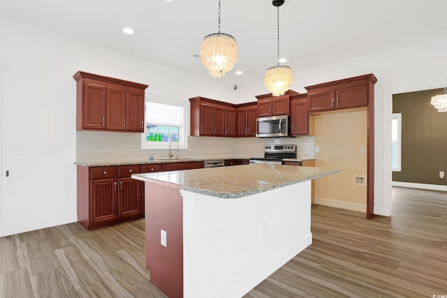 kitchen with decorative backsplash, a chandelier, stainless steel appliances, decorative light fixtures, and a sink