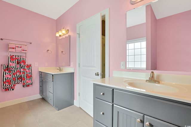 bathroom with two vanities, baseboards, tile patterned flooring, and a sink