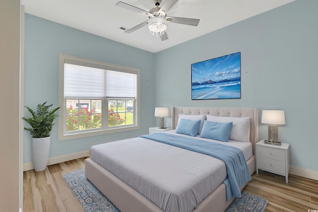 bedroom featuring a ceiling fan, light wood-style flooring, and baseboards