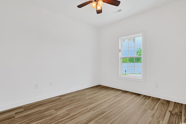 unfurnished room featuring visible vents, light wood-type flooring, a ceiling fan, and baseboards