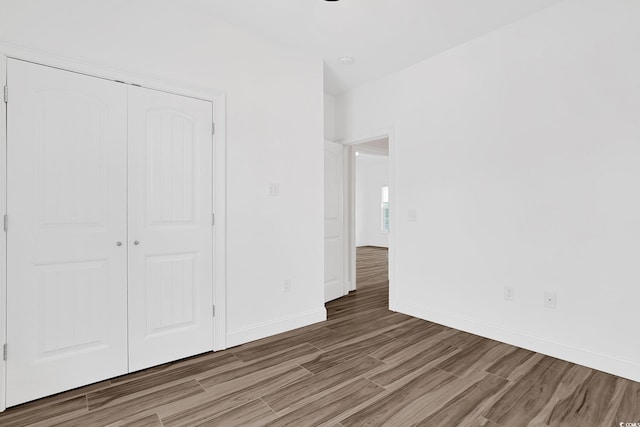 unfurnished bedroom with baseboards, a closet, and light wood finished floors