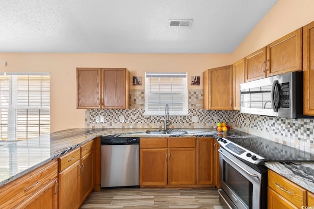 408 Chesterfield Ct, Myrtle Beach, SC 29577 - kitchen with appliances with stainless steel finishes, a sink, brown cabinetry, and a textured ceiling