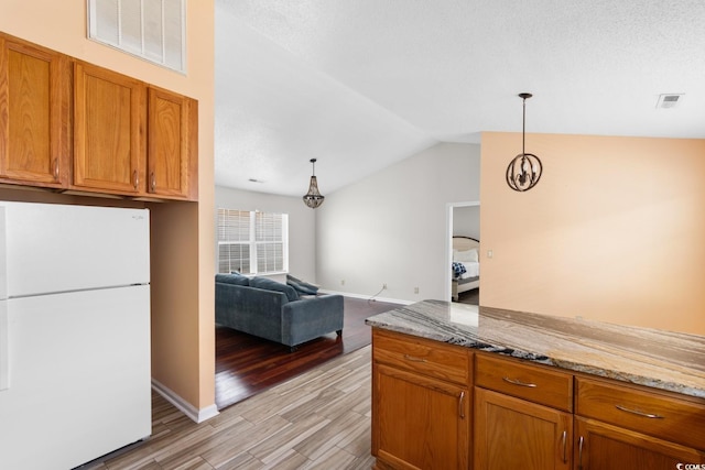 408 Chesterfield Ct, Myrtle Beach, SC 29577 - kitchen featuring freestanding refrigerator, light wood-style floors, vaulted ceiling, brown cabinetry, and light stone counters