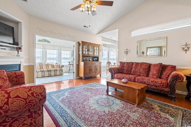 living room featuring plenty of natural light, a ceiling fan, a textured ceiling, and lofted ceiling