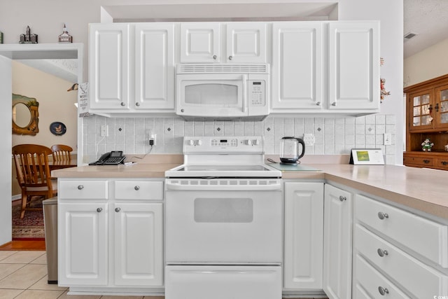 kitchen with light countertops, backsplash, white cabinets, and white appliances