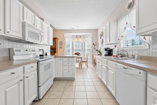 kitchen with a sink, white cabinets, white appliances, and a healthy amount of sunlight