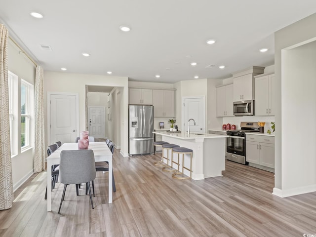kitchen featuring a sink, appliances with stainless steel finishes, a kitchen breakfast bar, and light wood-type flooring