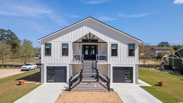 view of front facade with a front lawn, board and batten siding, an attached garage, driveway, and stairway
