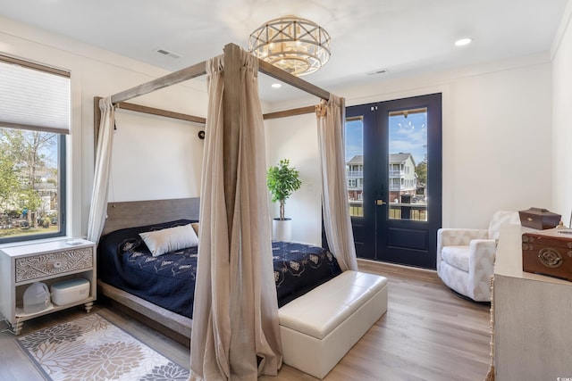 bedroom featuring access to outside, visible vents, and wood finished floors