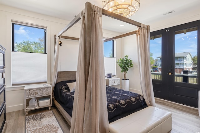 bedroom with french doors, multiple windows, wood finished floors, and access to exterior