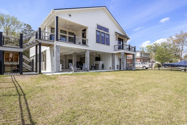 rear view of property with fence, stairs, a patio area, a balcony, and a lawn