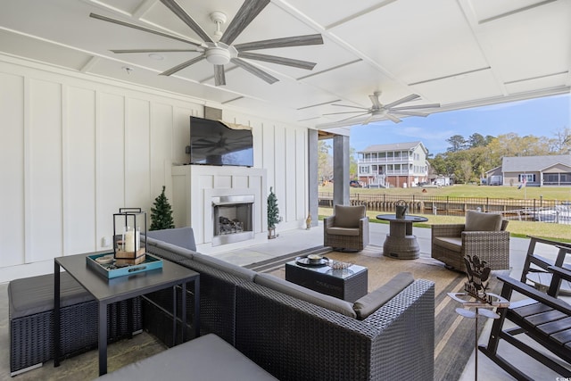 view of patio / terrace featuring fence, a ceiling fan, and an outdoor living space with a fireplace