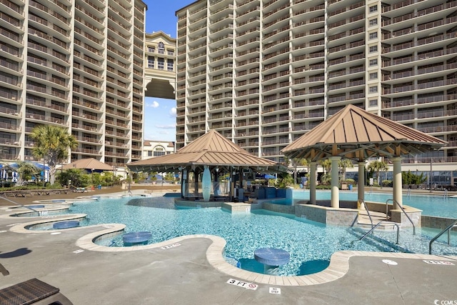 community pool featuring a jacuzzi, a gazebo, and a patio area