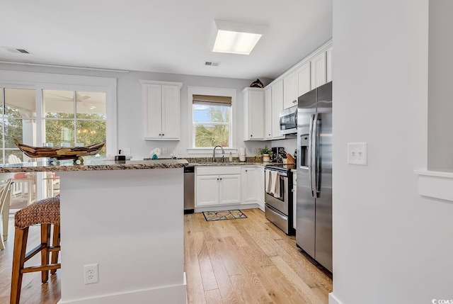 kitchen featuring visible vents, a sink, light wood finished floors, and appliances with stainless steel finishes