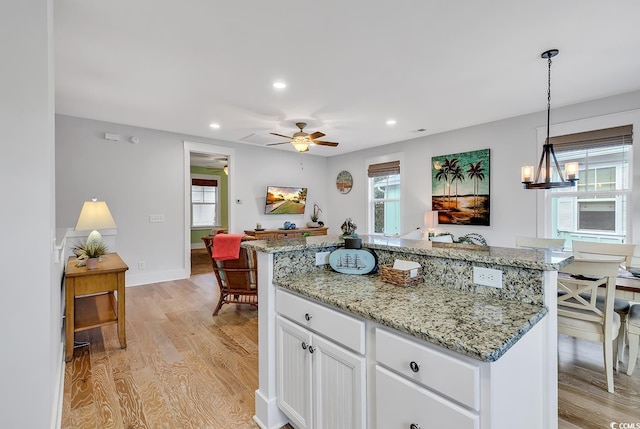 kitchen featuring ceiling fan, plenty of natural light, light wood finished floors, and a center island