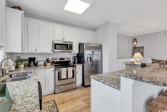 kitchen featuring white cabinetry, appliances with stainless steel finishes, a sink, and light wood-style flooring
