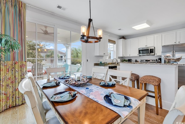 dining room featuring visible vents, light wood-style flooring, and an inviting chandelier
